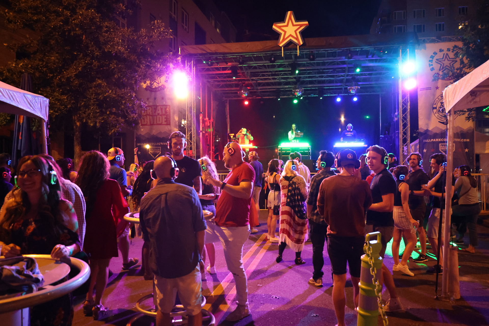 Nighttime crowd wearing light-up headphones in front of a lit stage at Stars & Stripes Streetfest